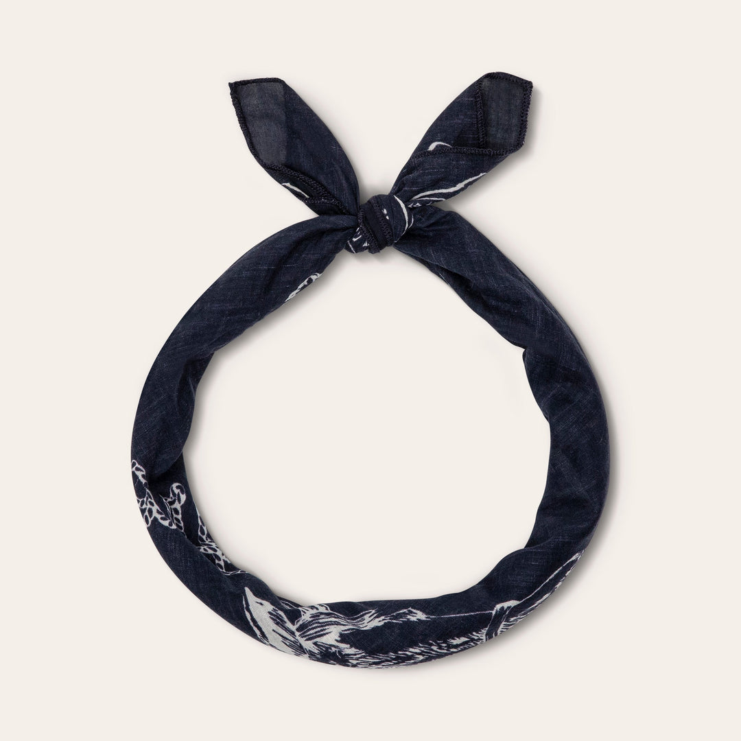 Navy blue bandana with white paisley print tied in bow shape on neutral background