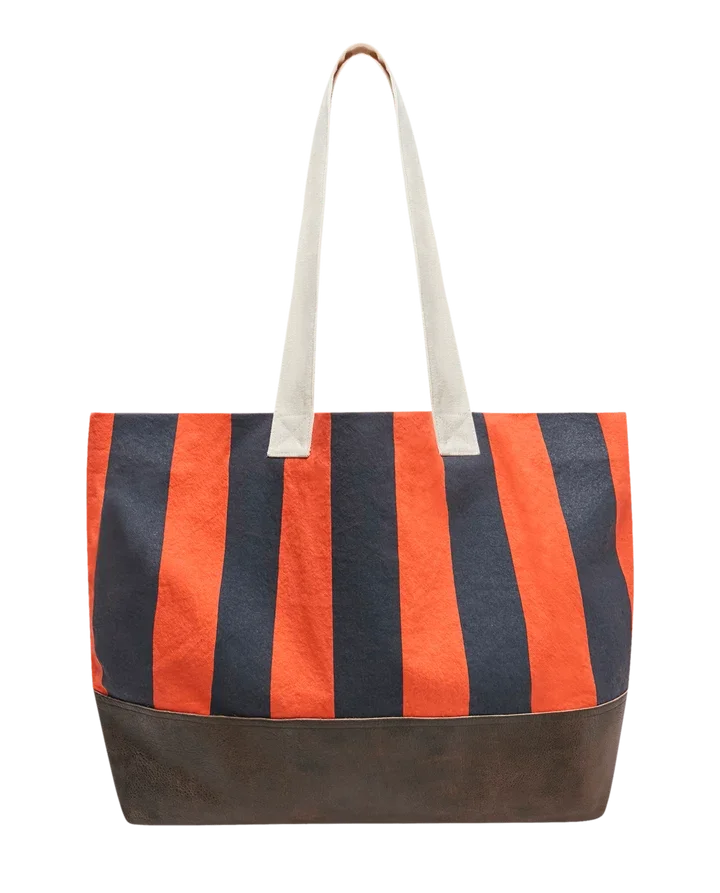 The Great Stripe Tote bag in orange and navy vertical stripes with cream handles and brown leather base
