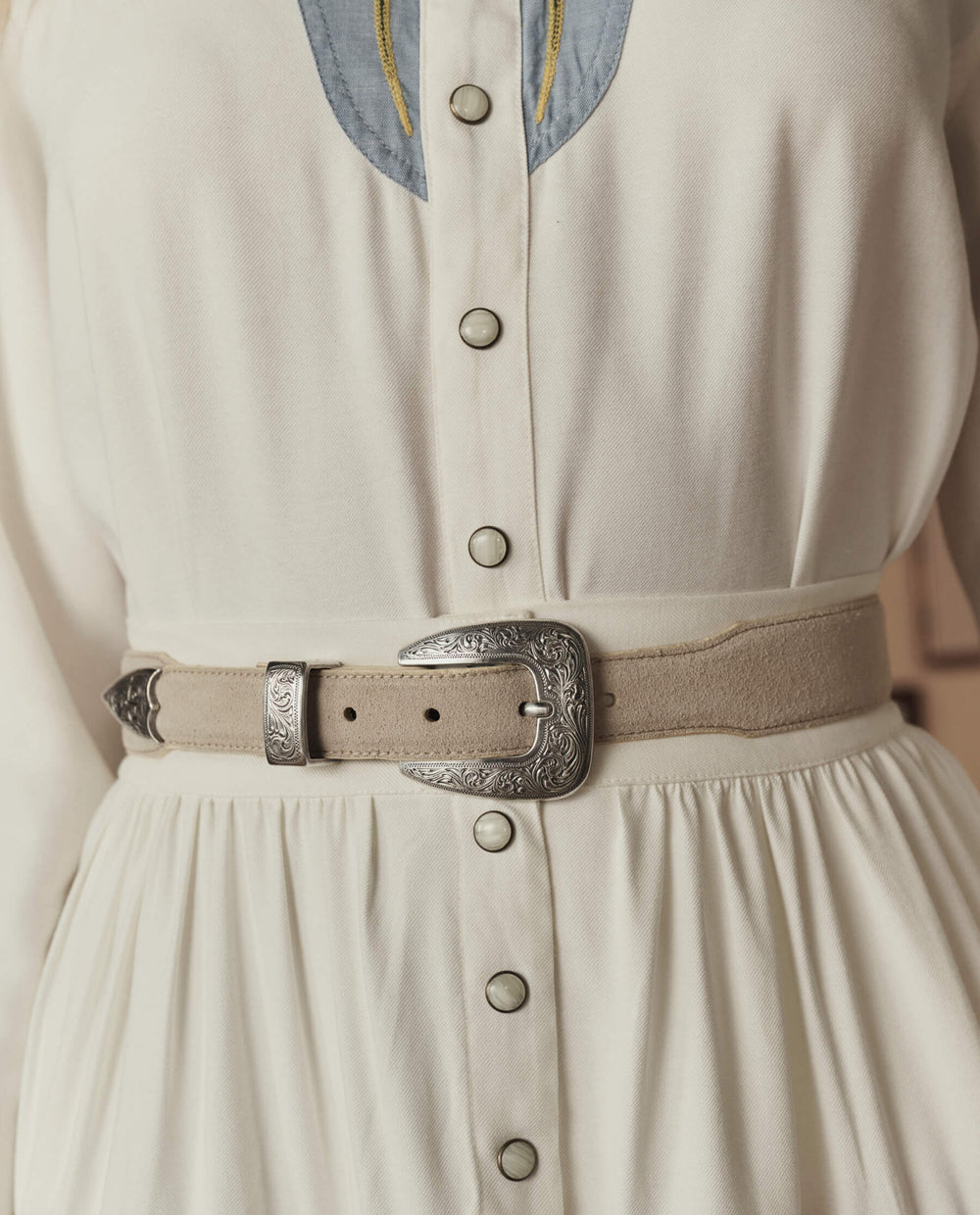 The Great Western Narrow Belt in tan suede with ornate silver buckle worn with cream dress