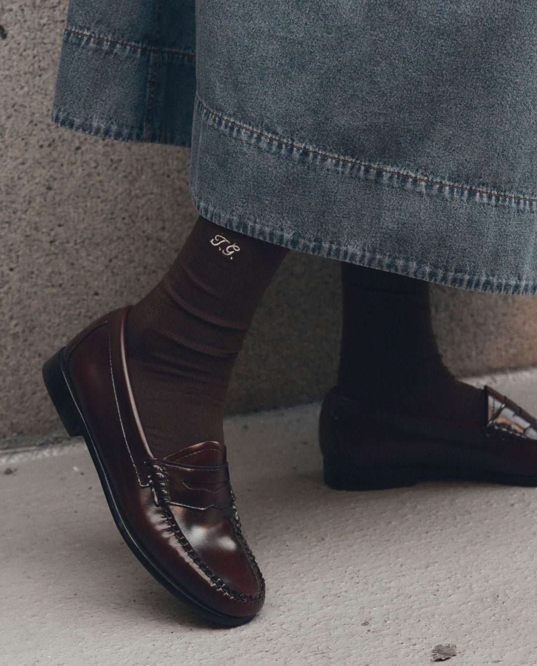 Dark brown monogrammed trouser socks with embroidered initials styled with burgundy penny loafers and denim skirt