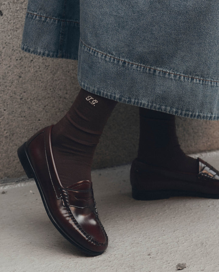 Dark brown monogrammed trouser socks with embroidered initials styled with burgundy penny loafers and denim skirt